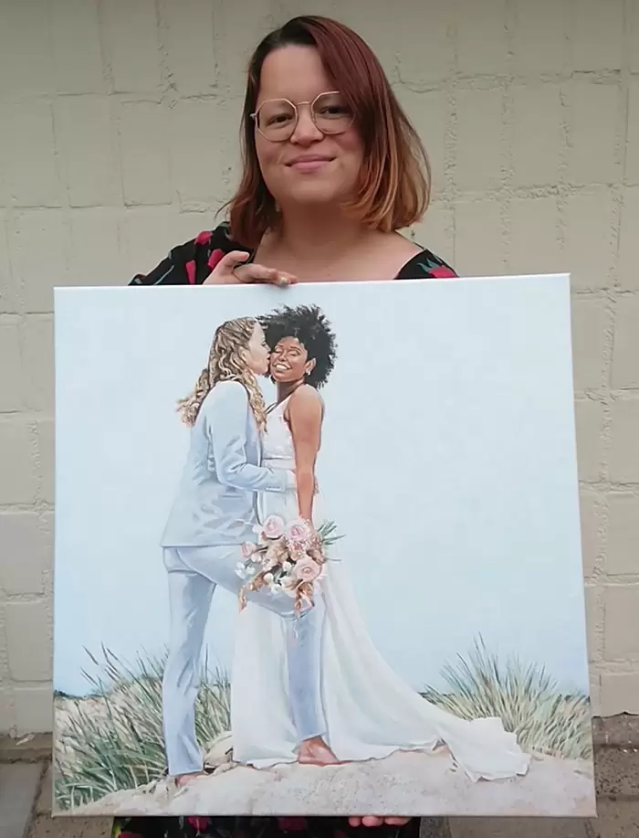 Renée holding a square beach wedding painting.